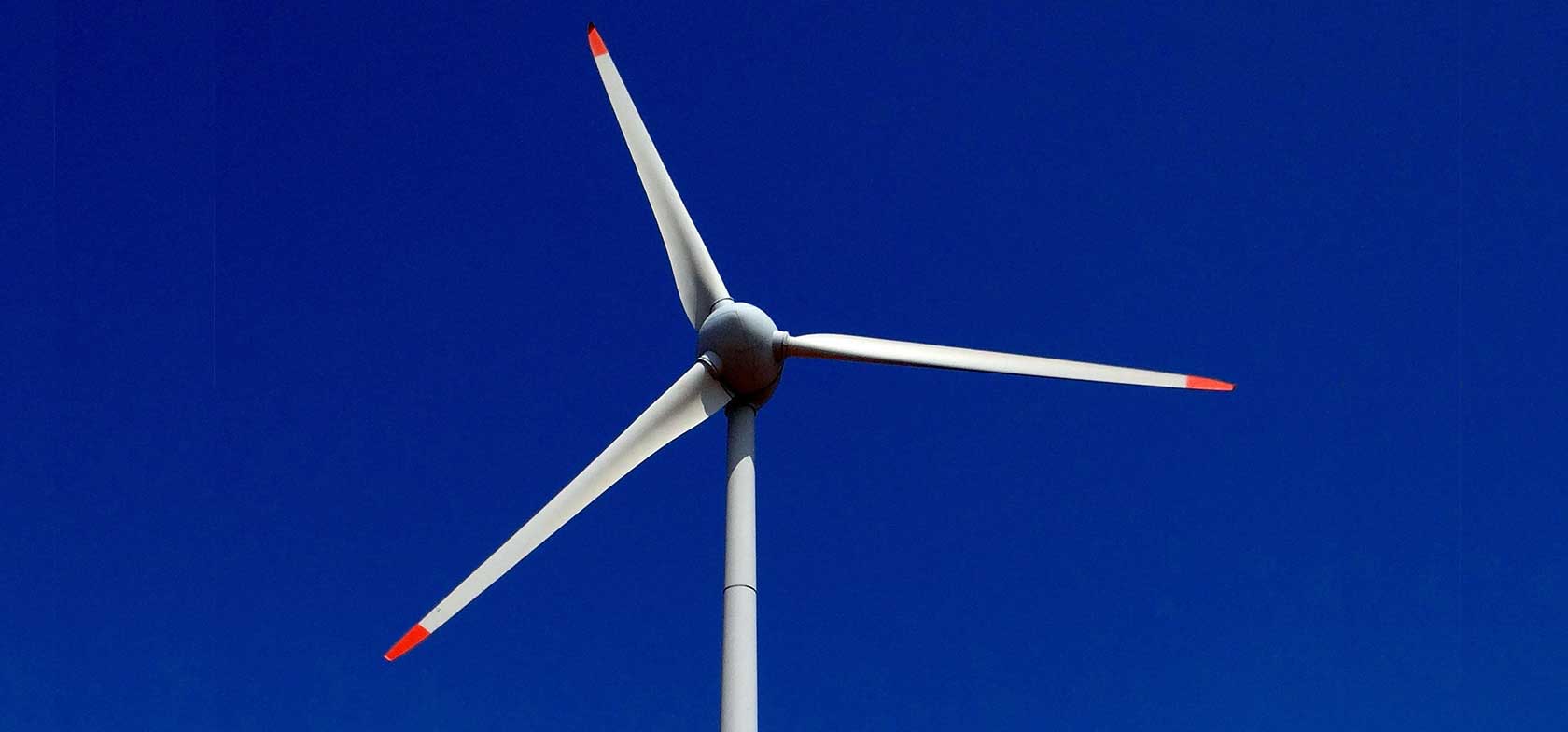 Single wind turbine against blue sky